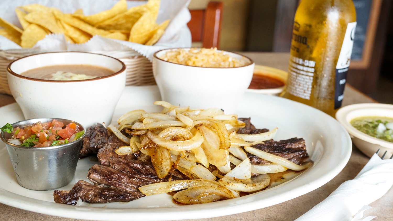 Carne Asada: Tender, grilled skirt steak, cooked to order. Served with rice, beans, grilled onions, pico de gallo and tortillas.
